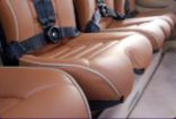 Close-up of brown leather seats with seatbelts.