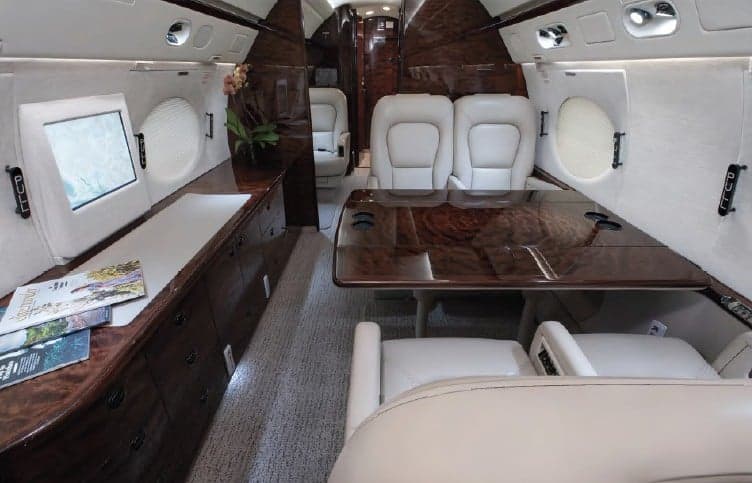 Interior view of the aircraft with cream-colored leather seats and wood accents.