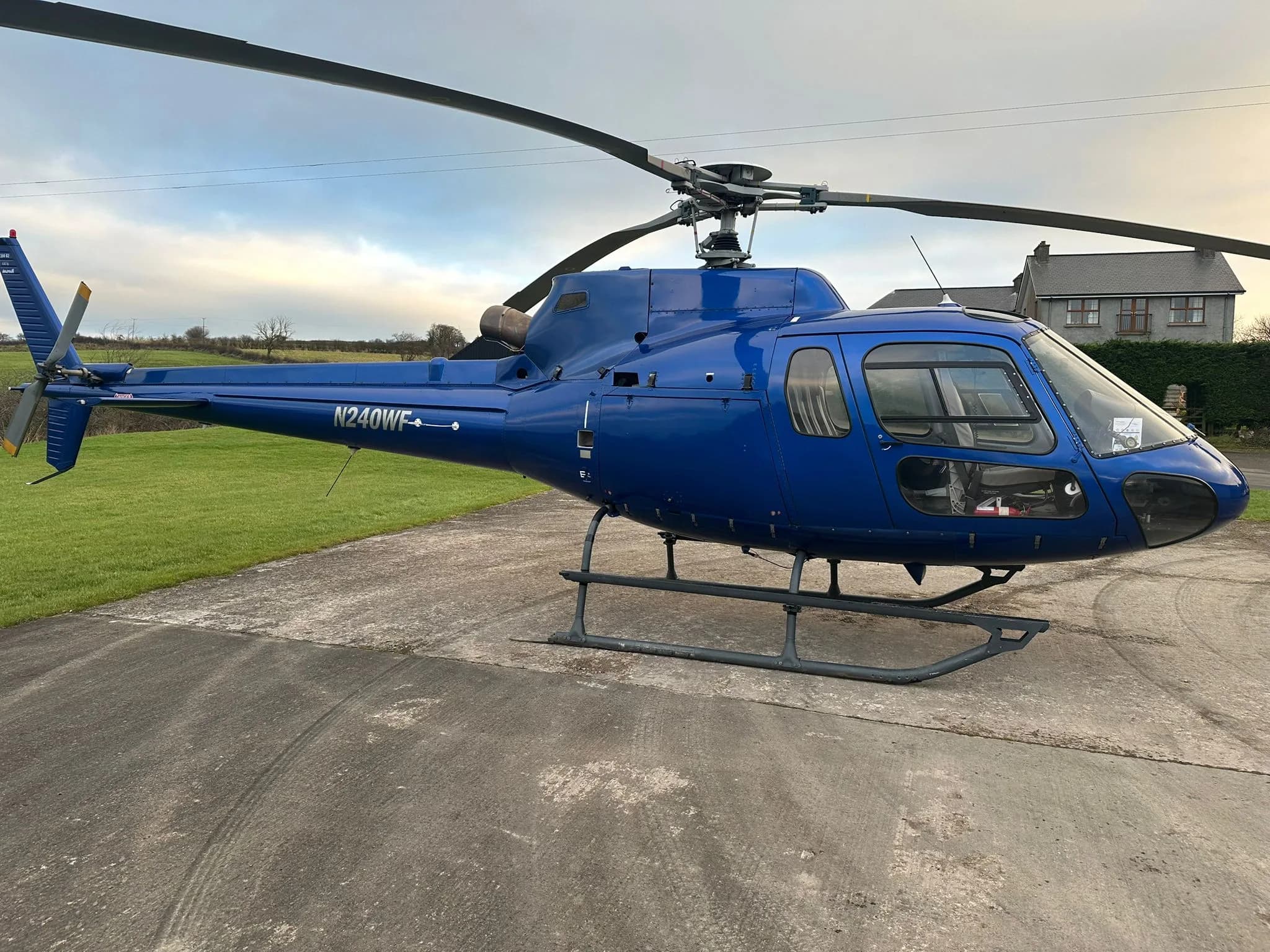 Side view of the blue N240WF helicopter parked on the ground.