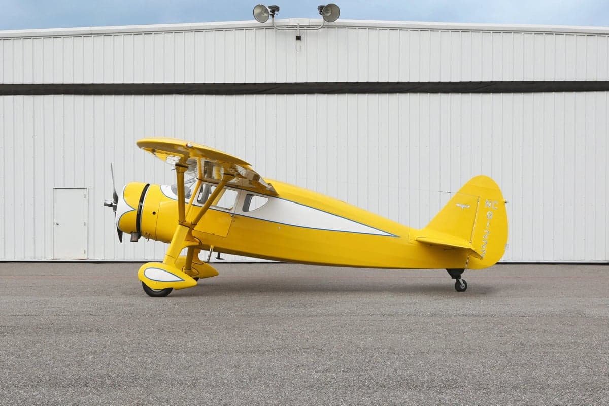 Side view of a yellow and white Stinson Reliant parked on the tarmac.