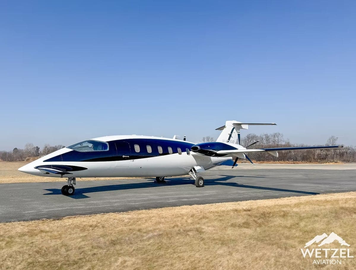 A Piaggio Avanti EVO aircraft is parked on the tarmac with a blue and white paint scheme.