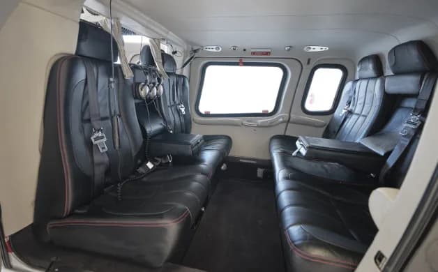 View of the helicopter's interior with black leather seats and headsets.