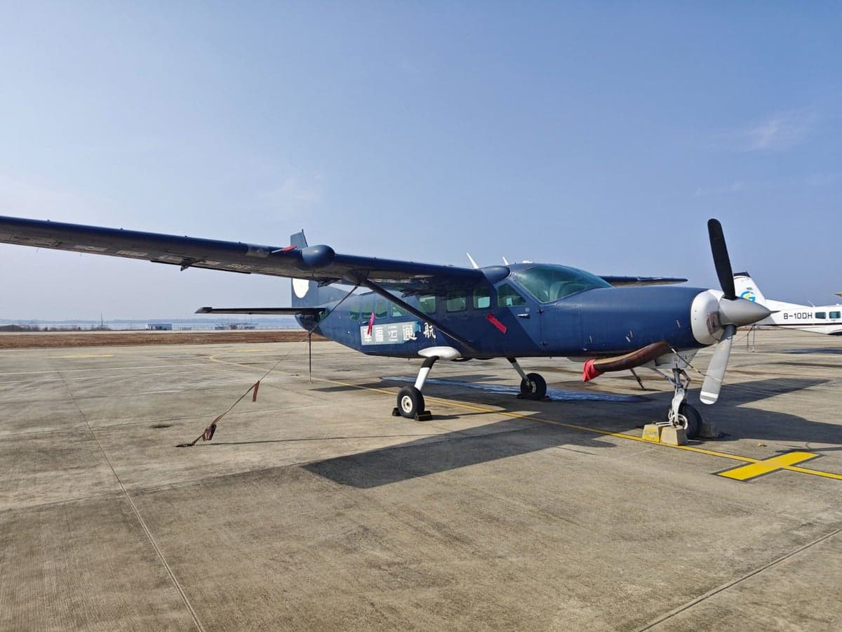A blue aircraft is parked on the tarmac on a sunny day.