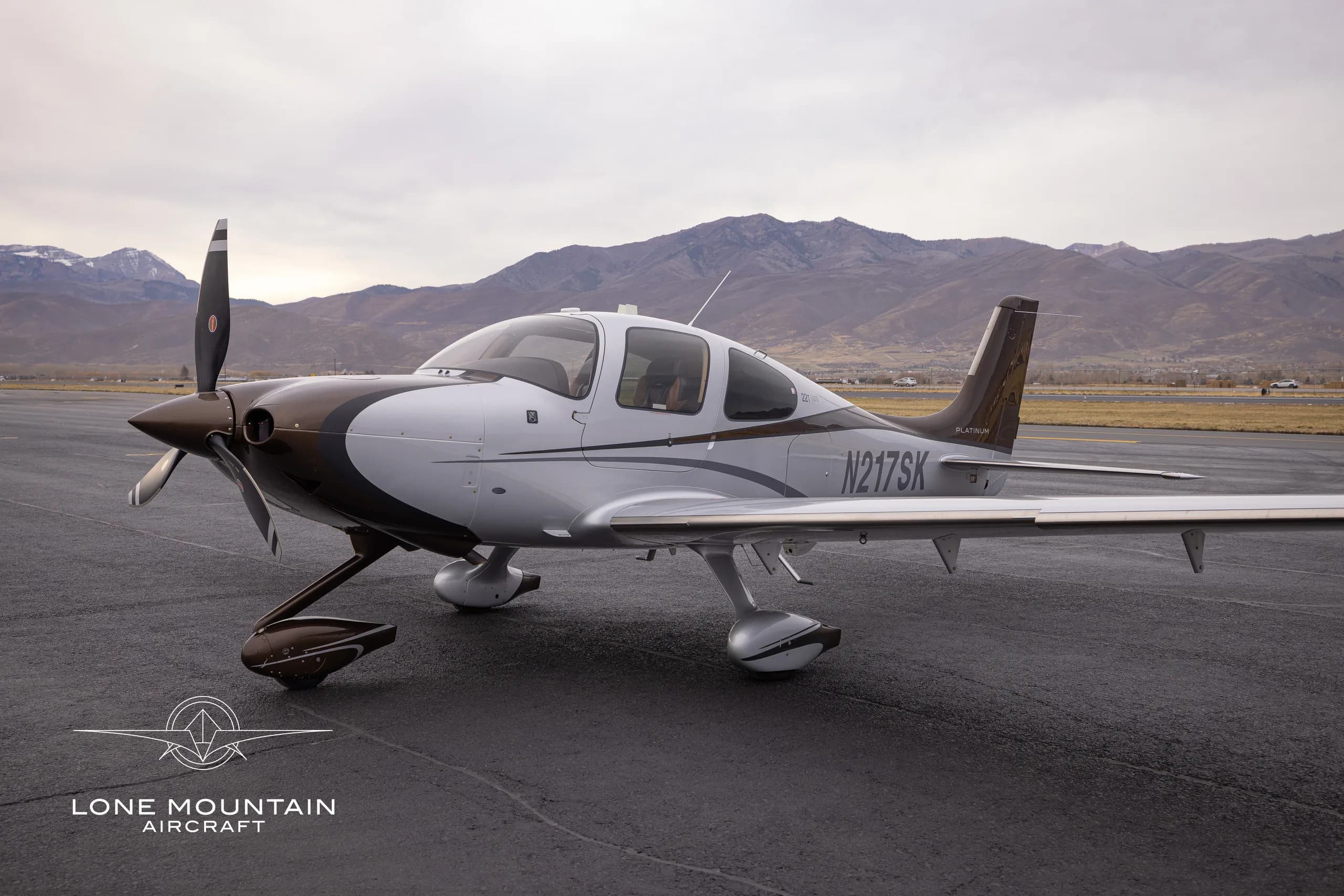 A Cirrus SR22T aircraft with a brown and white paint scheme is parked on the tarmac.
