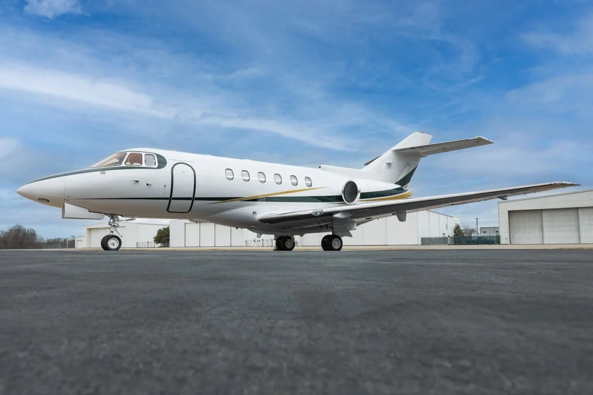 Hawker 800XP on the tarmac with a white and gold paint scheme.