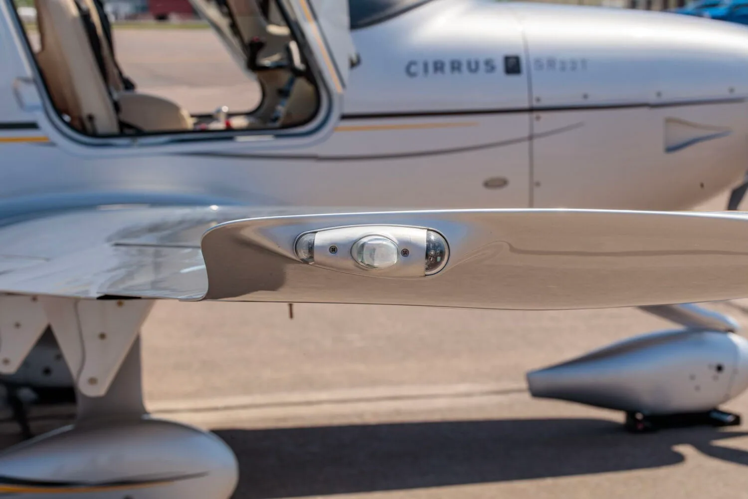 A close-up view of the wingtip light and part of the propeller of the silver Cirrus SR22T aircraft.