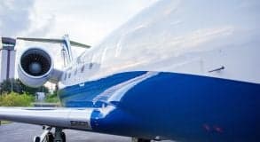 Close up of the side of a Challenger aircraft showing the engine and blue and white paint scheme.