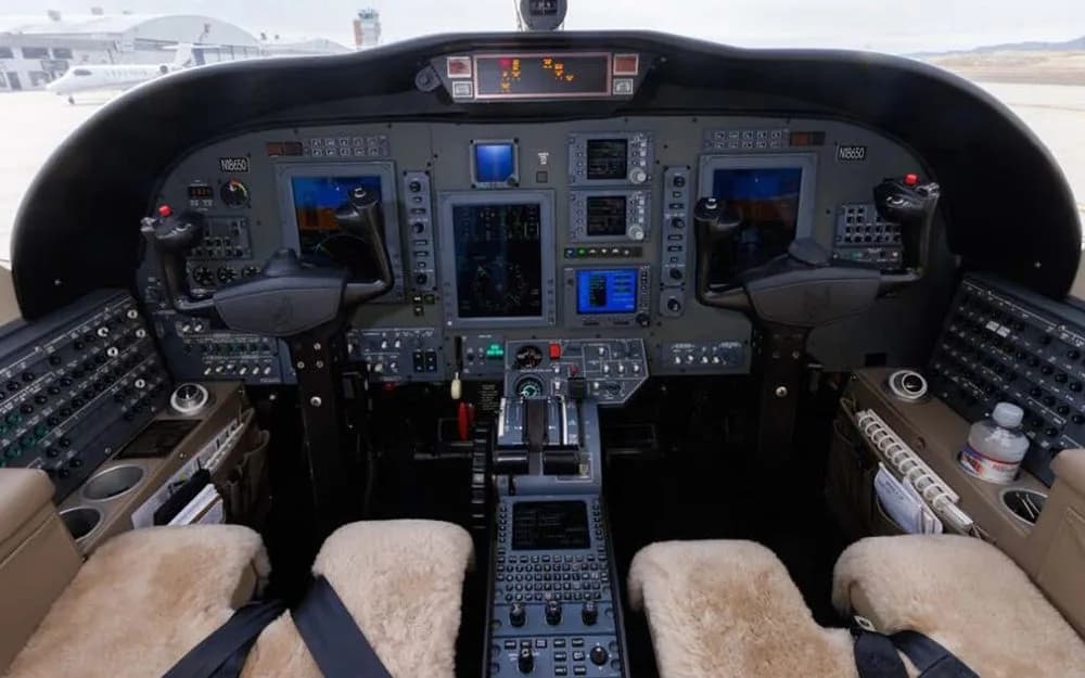 The cockpit of a business jet with multiple display screens and control panels.
