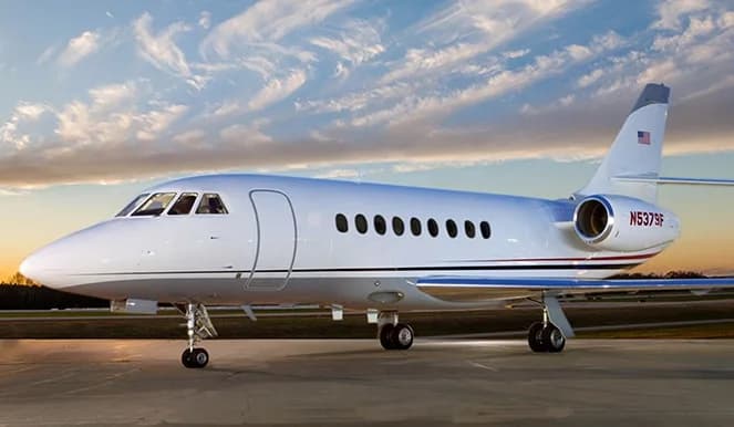 A white jet with registration N5379F is parked on the tarmac against a sunset sky.