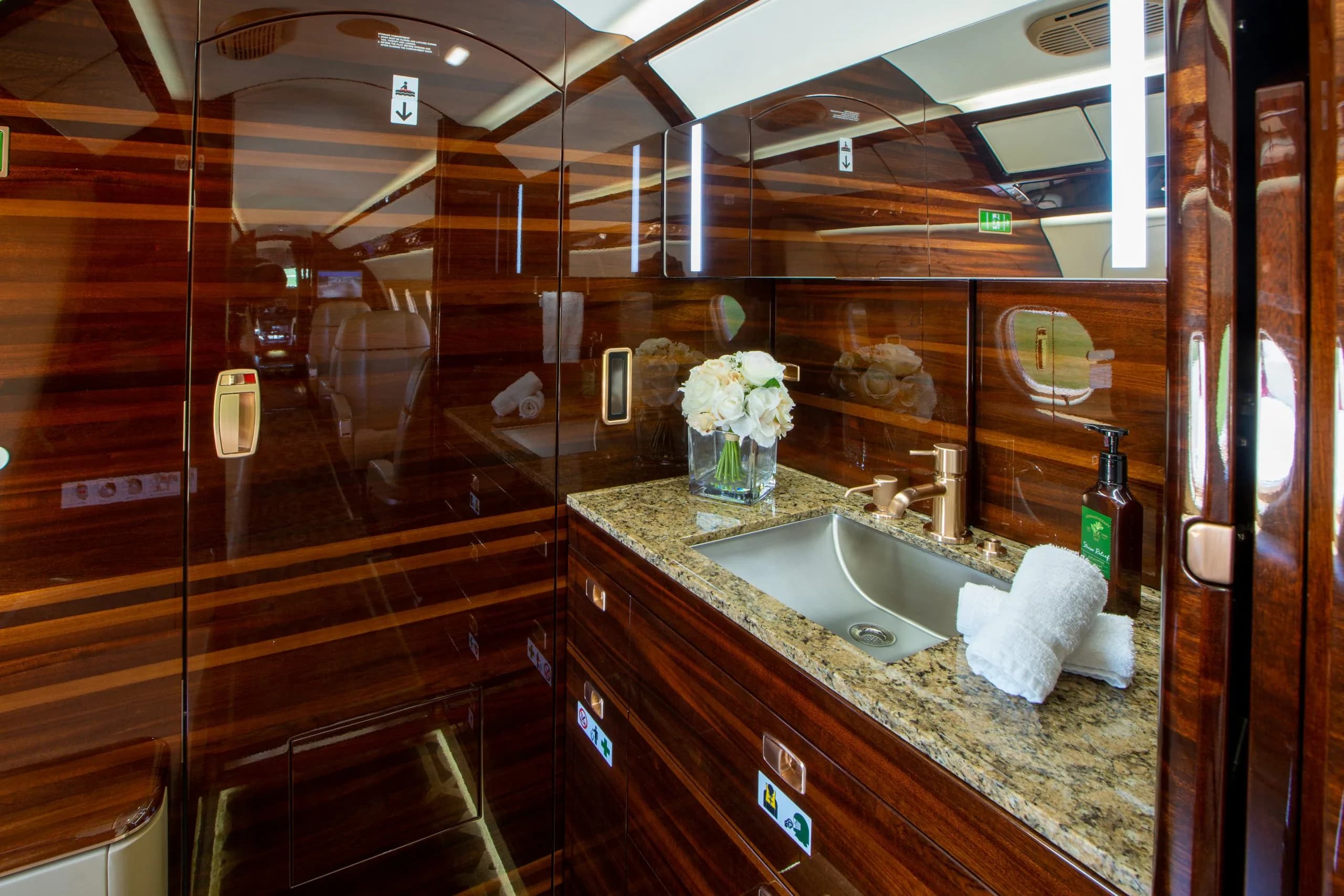 The lavatory of an Embraer Phenom 300E with wood paneling and granite countertop.