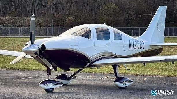 A white and dark purple Columbia 400 single-engine aircraft with registration N1266Y parked on a tarmac.