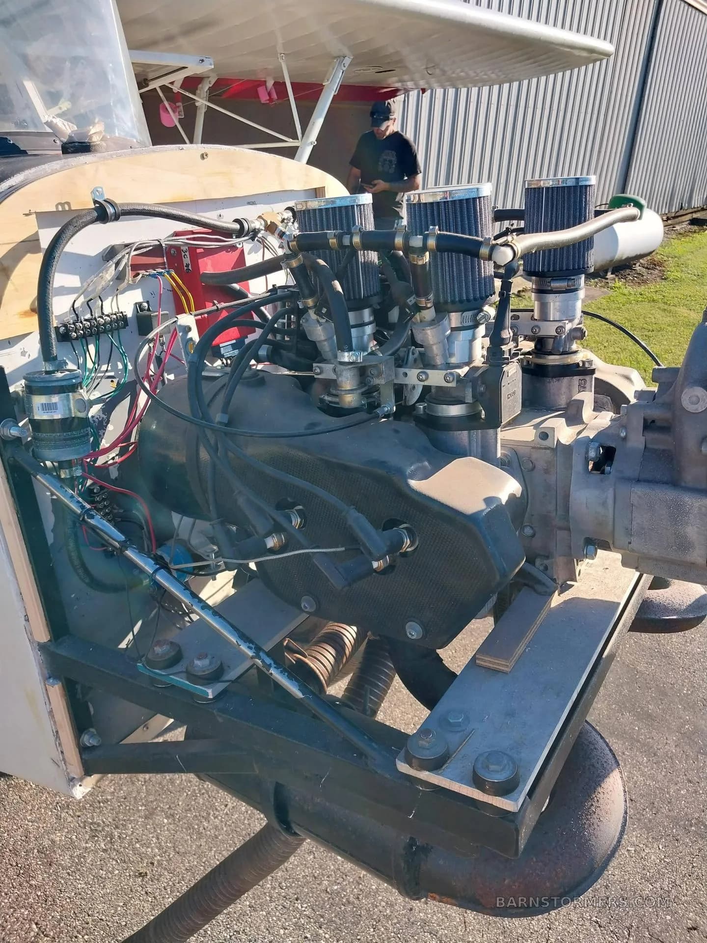 A close-up view of the exposed engine of a white experimental aircraft, showing carburetors and wiring.