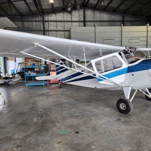 Side view of a white and blue aircraft parked inside a hangar.