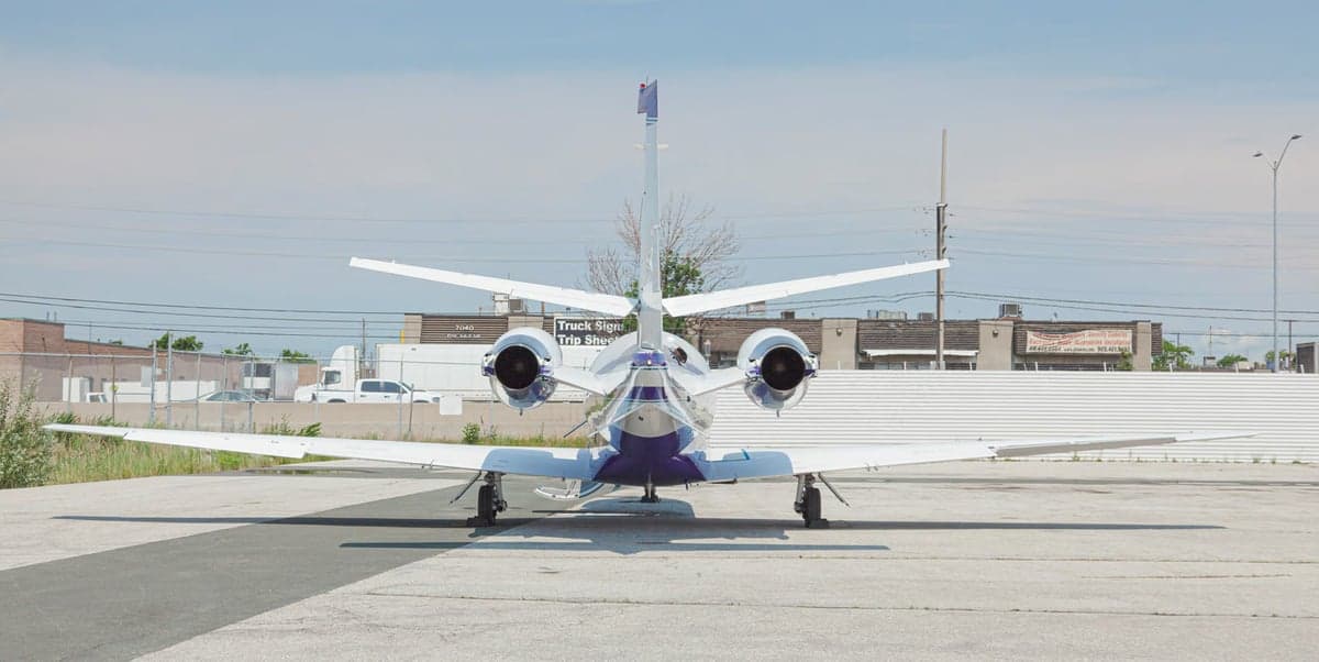 A white and purple jet aircraft parked on the tarmac.