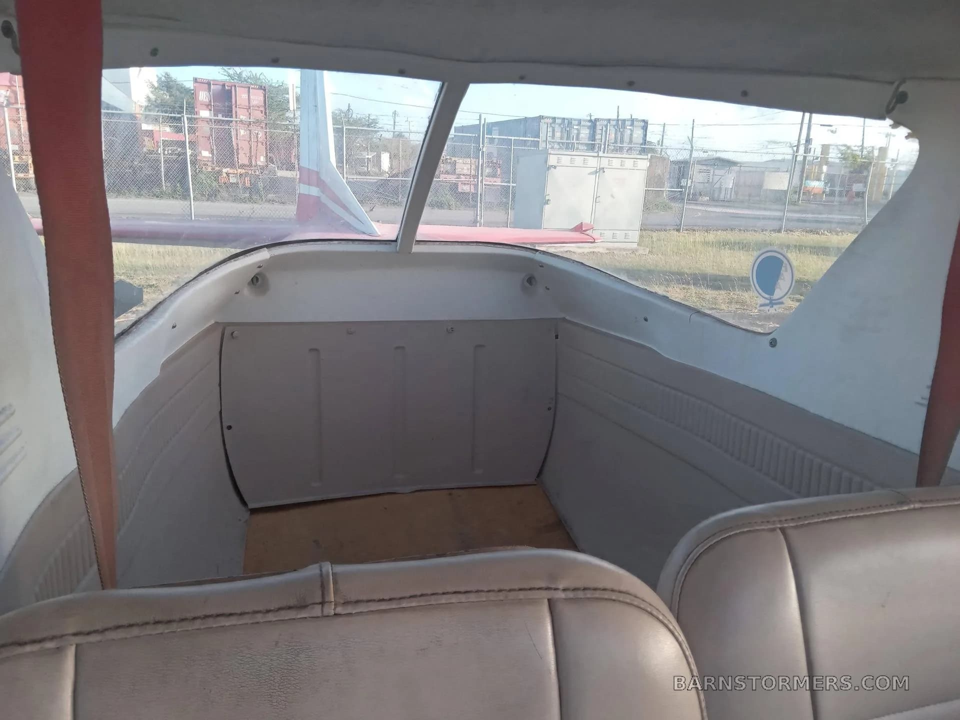 The interior rear cabin of a light aircraft, showing the back of the front seats and the cargo area.