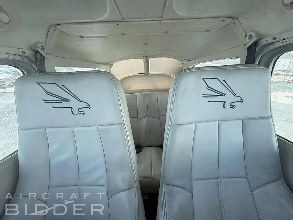 The light-colored leather seats of the aircraft interior, each embroidered with an eagle logo.