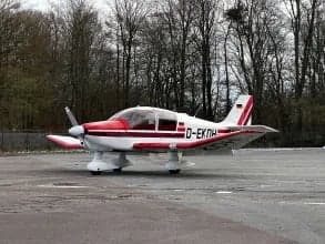 Side view of a white and red aircraft with German flag on the tail, parked on the tarmac.