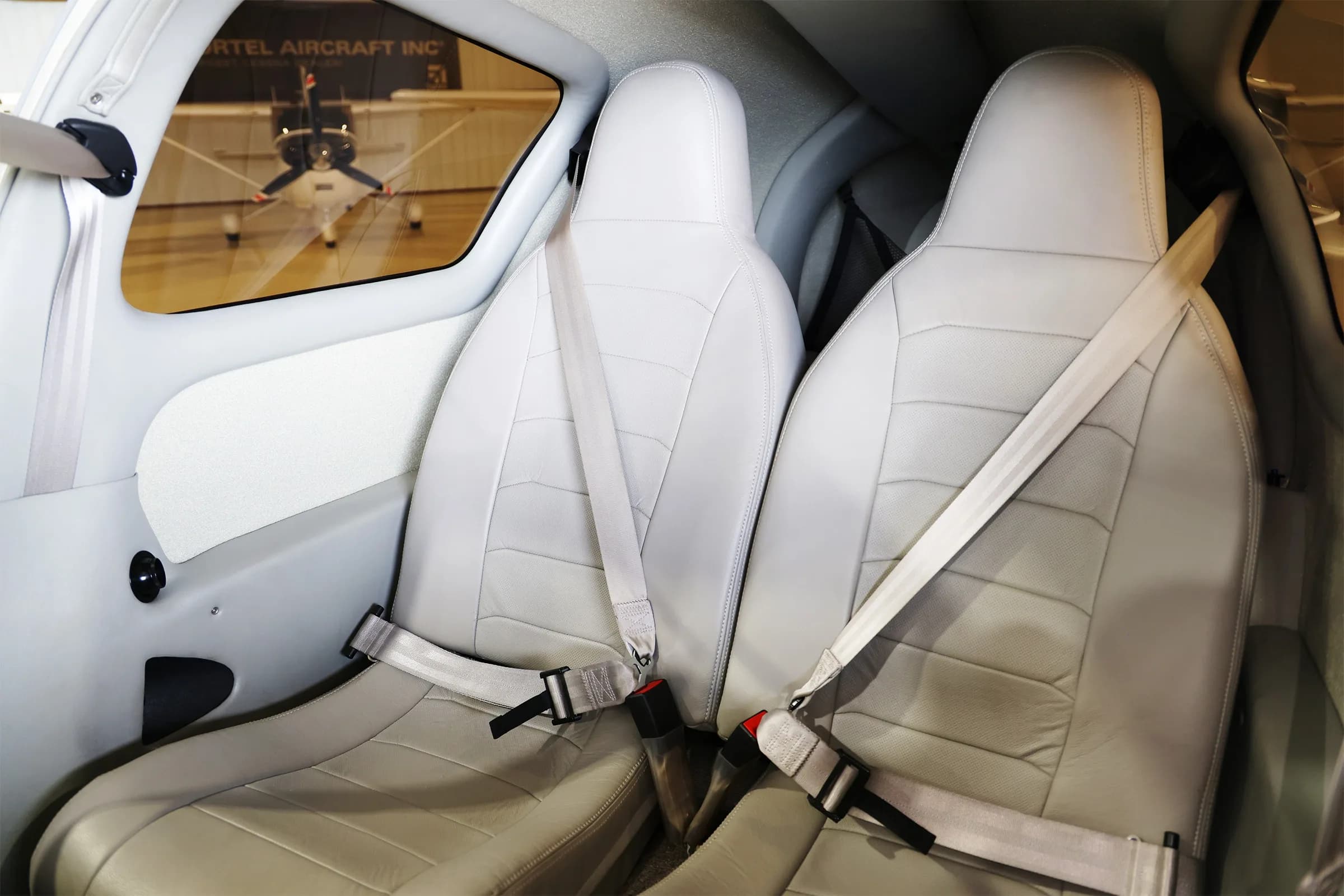 The light gray interior cabin seats of the Cessna TTx aircraft, with a view of another aircraft outside the window.