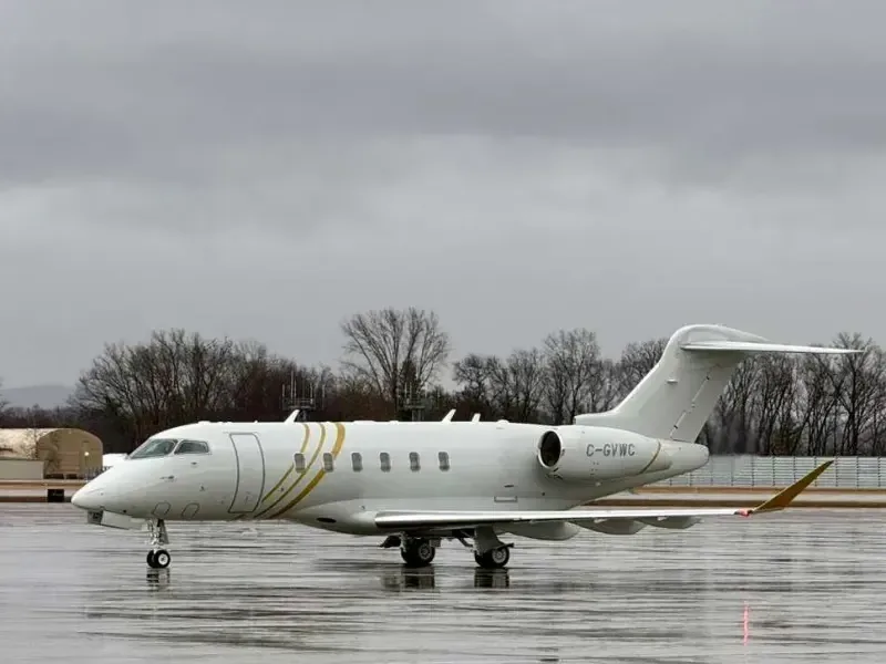 Side view of a Challenger aircraft with a white and gold paint scheme on the tarmac.