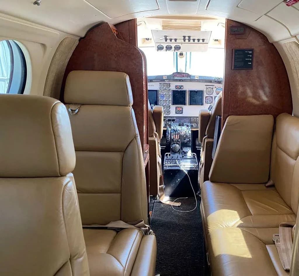 View from the aircraft cabin showing tan leather seats and a clear view into the cockpit.