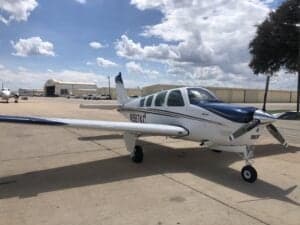 Beechcraft Bonanza N987KC on the ramp with a hangar in the background.