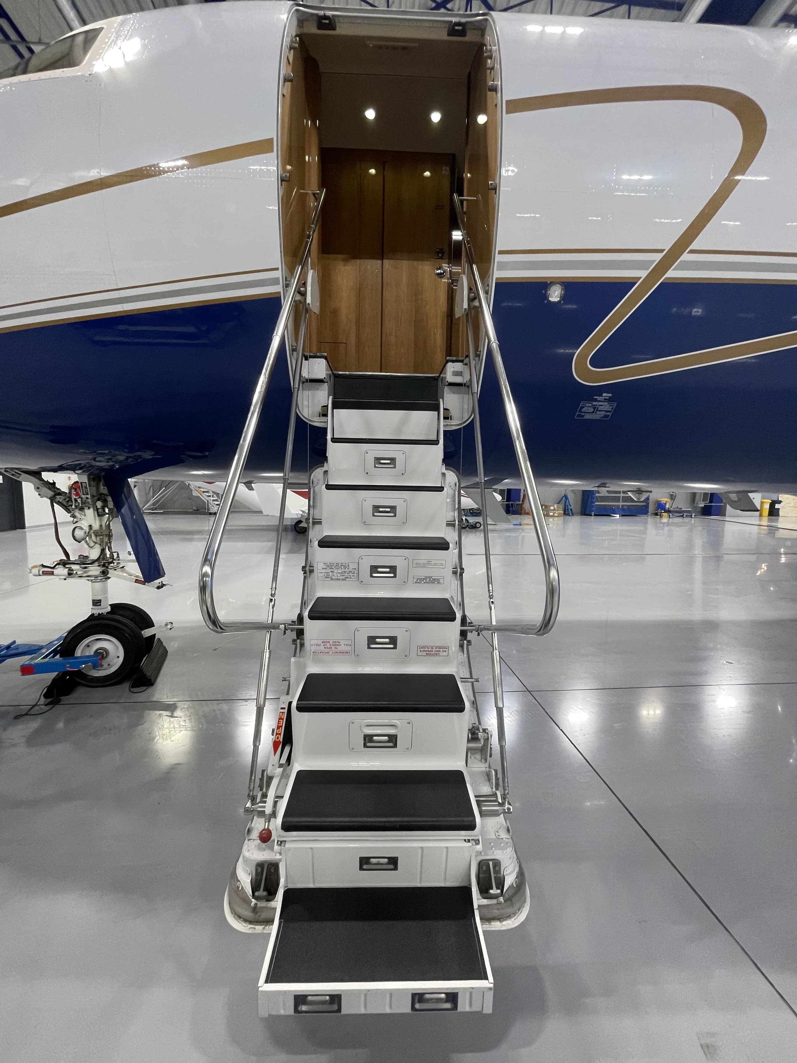 The open entry door and integrated stairs of a private jet, showing the interior hallway.