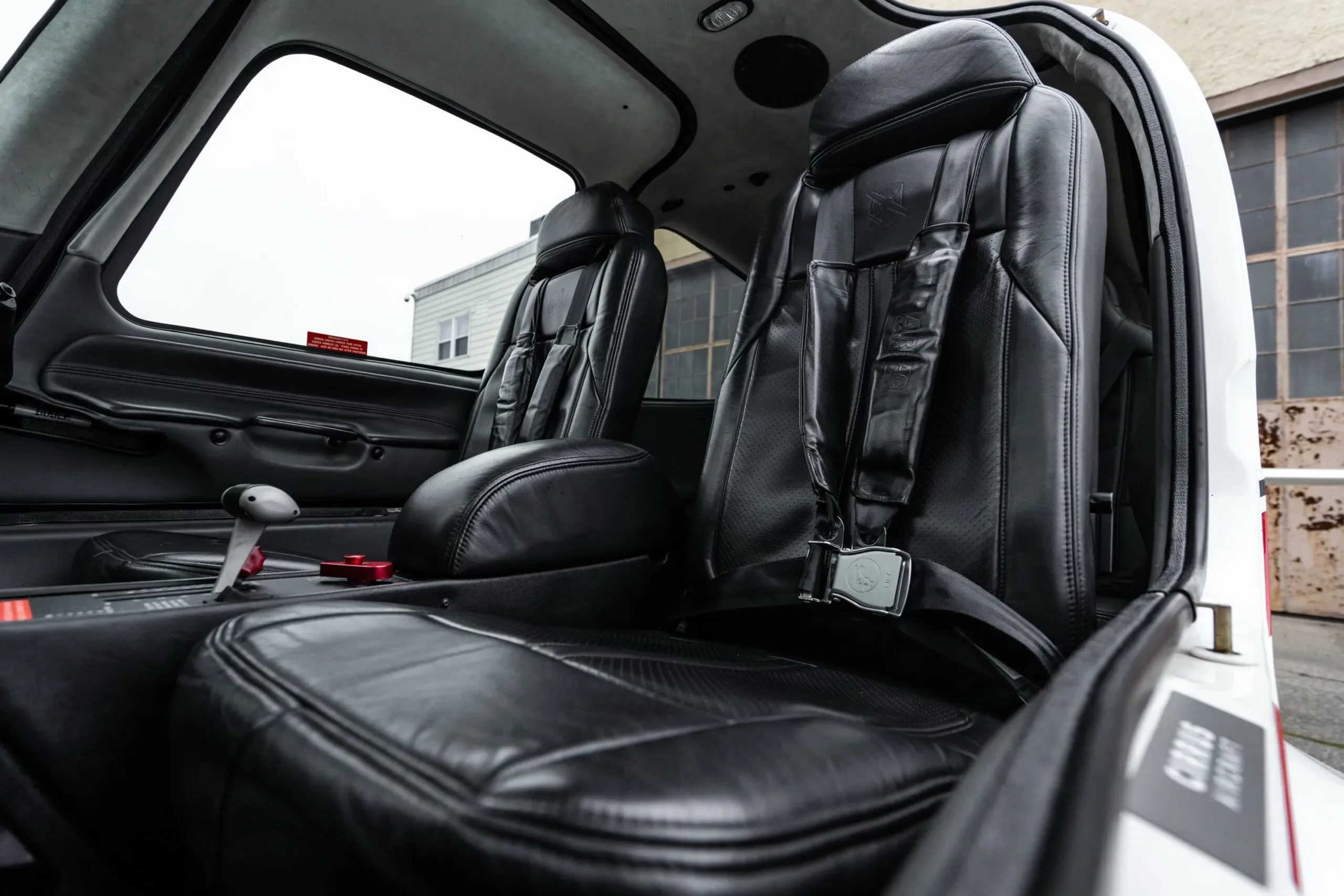 The black leather front seats of the aircraft cabin, viewed from the open door.