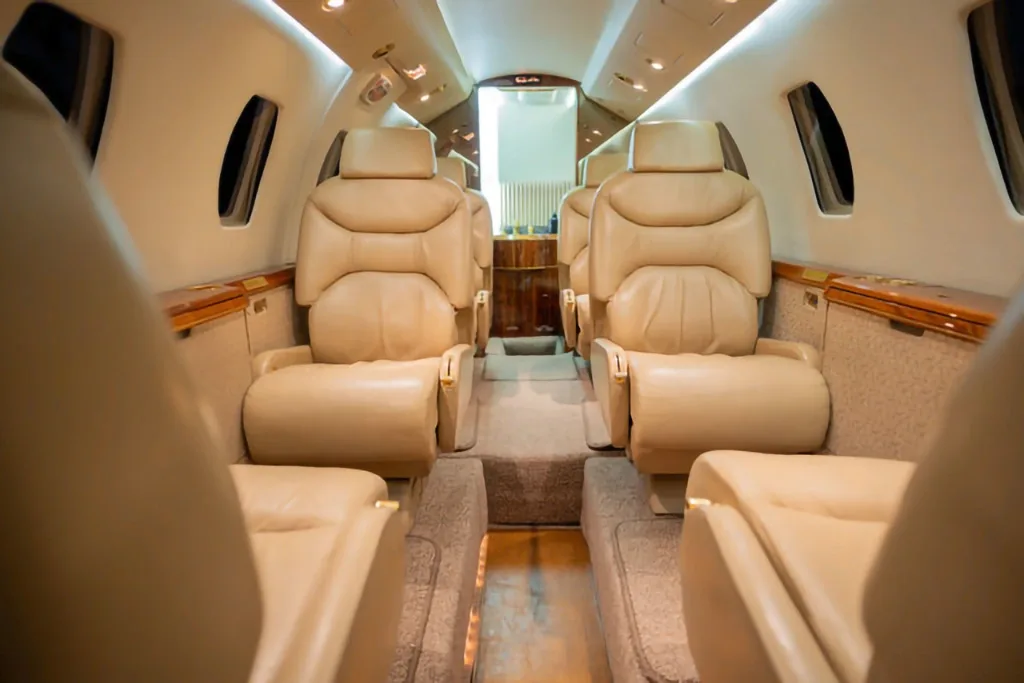 The aircraft's interior cabin features beige leather seats and light wood trim.