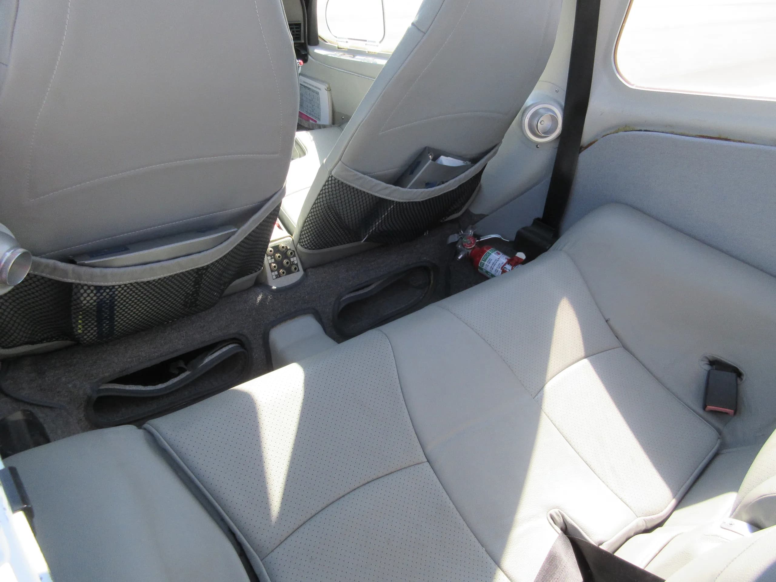 The light gray rear seats and floor of a Diamond aircraft interior, with a fire extinguisher visible.