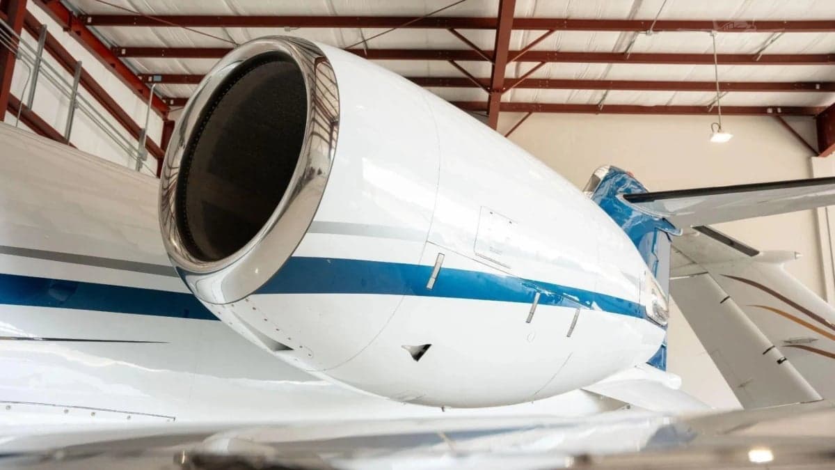 Close-up of the white engine nacelle with a blue stripe on a Learjet 31A, inside a hangar.
