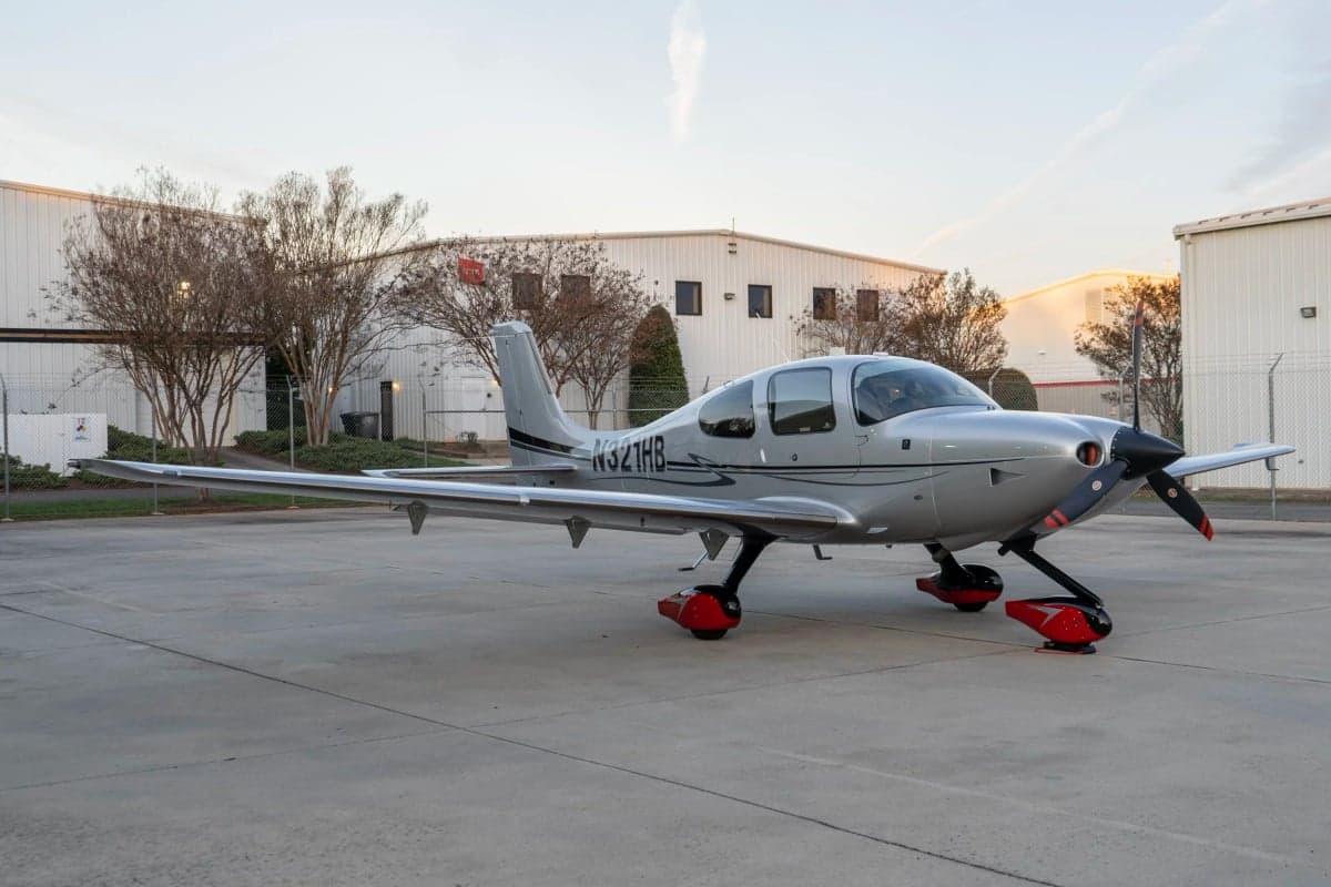 A Cirrus SR22T aircraft with a silver paint scheme parked on the tarmac.