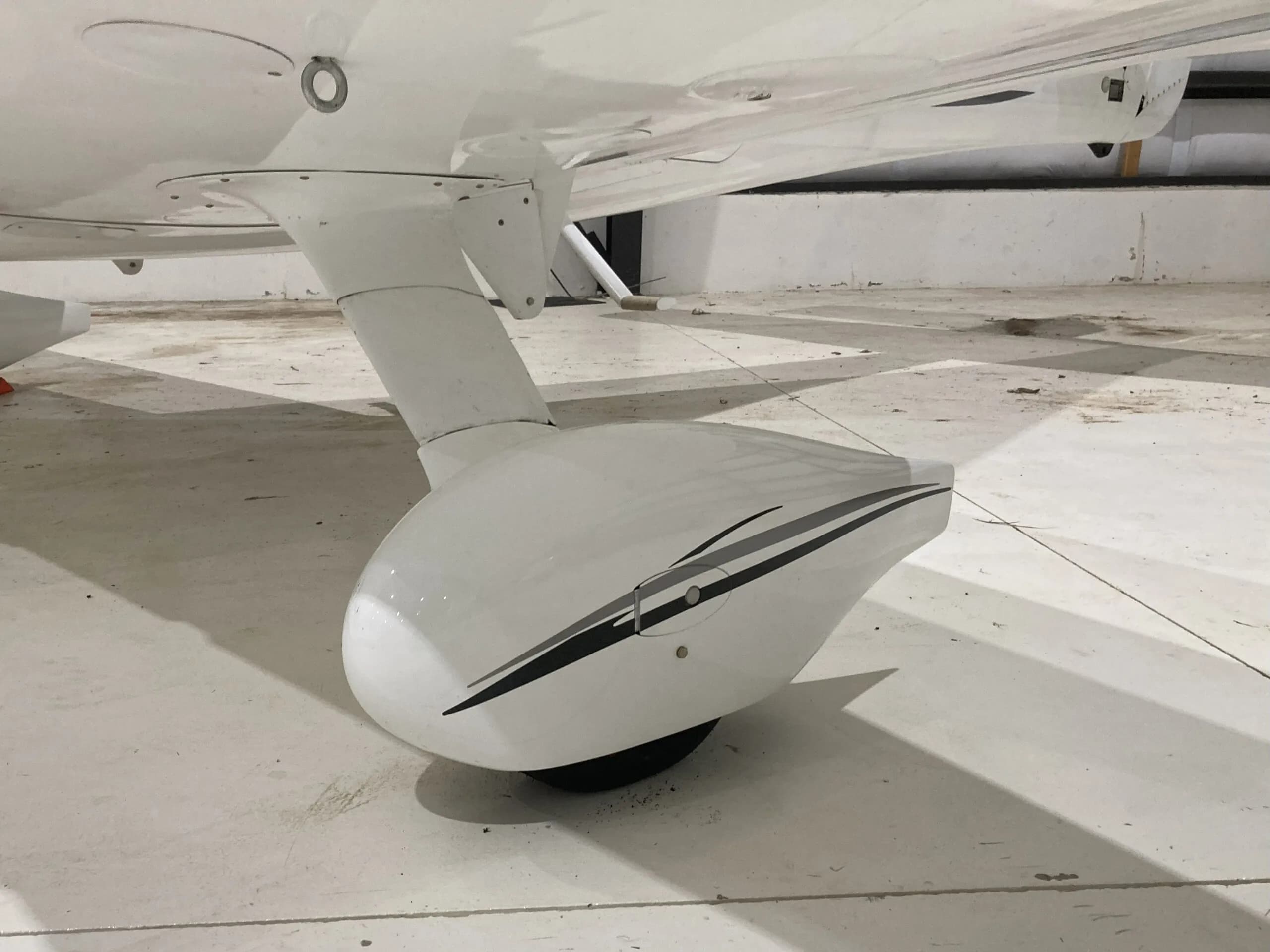 Close-up of the main landing gear fairing of a white Cirrus SR22 aircraft with black and grey stripes.