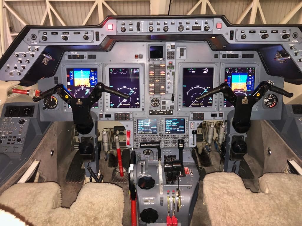 The detailed instrument panel of a business jet cockpit with multiple digital displays.