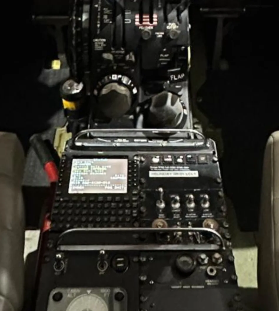 A close-up view of the throttle quadrant and center console with a display screen in an aircraft cockpit.