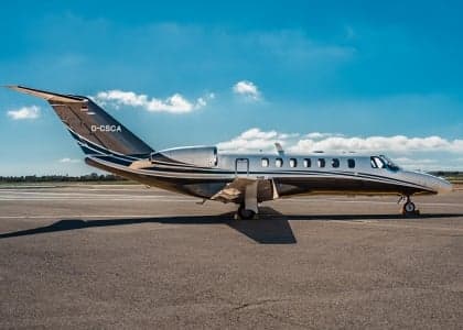 A Cessna Citation CJ1+ aircraft is parked on the tarmac with a blue sky background.
