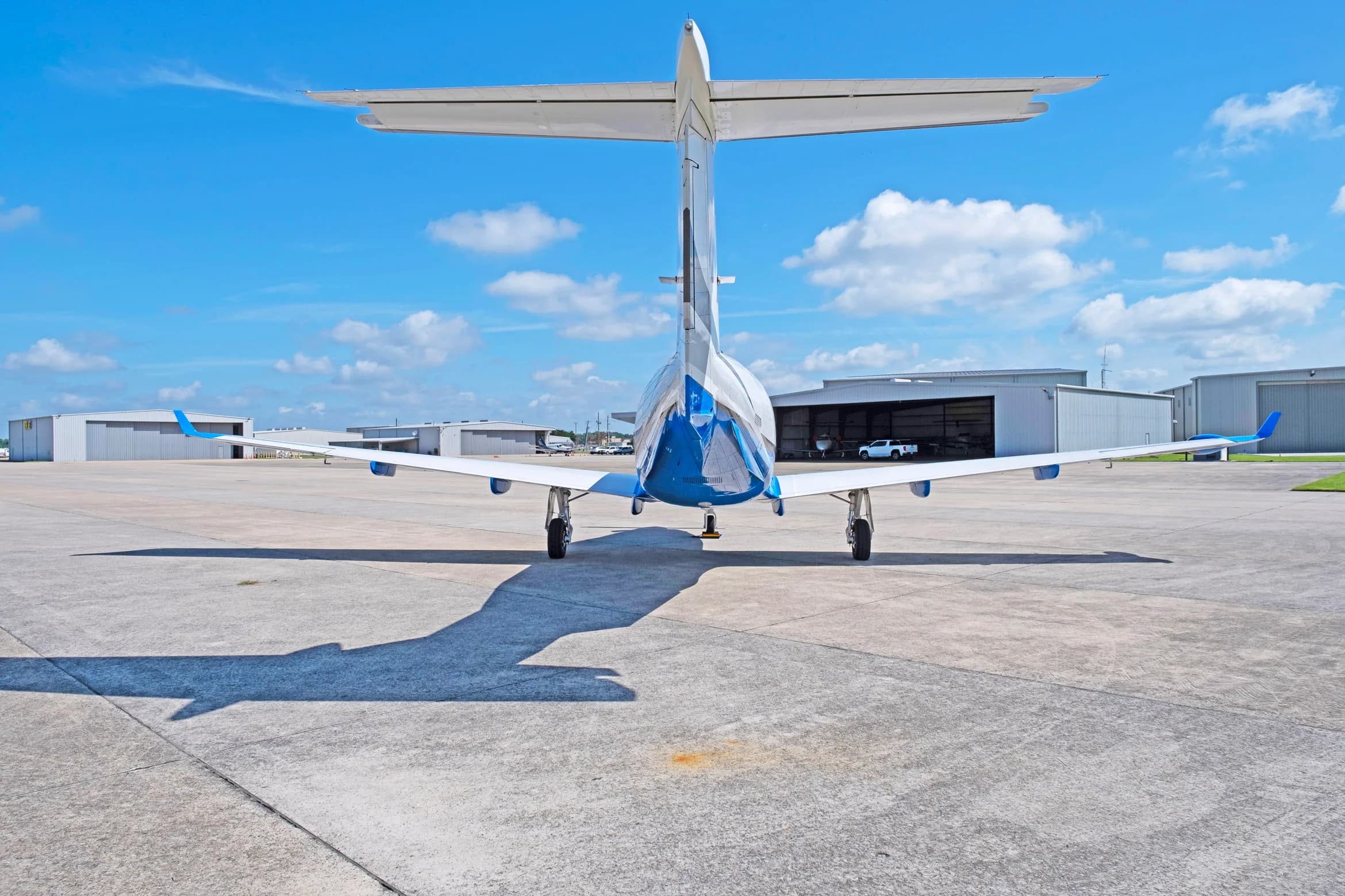A rear view of the white and blue Pilatus PC-12 aircraft, tail number N888NT, parked on a tarmac.