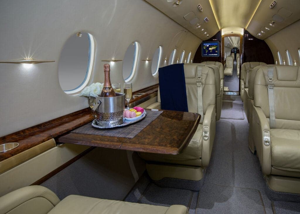 View of the interior cabin of a private jet with leather seats and wood accents.