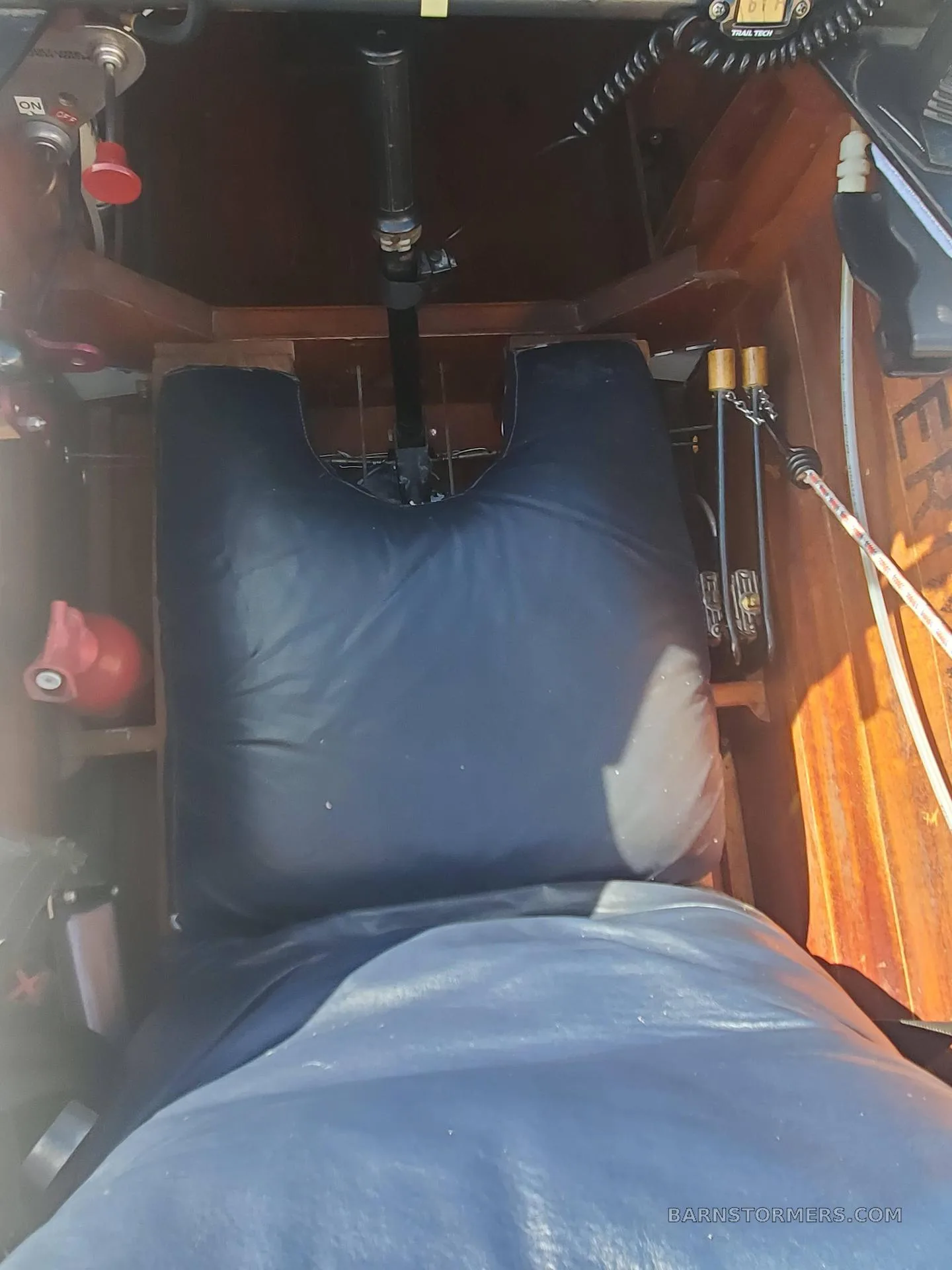 An overhead view of the aircraft's interior shows a black padded seat and wooden side panels.