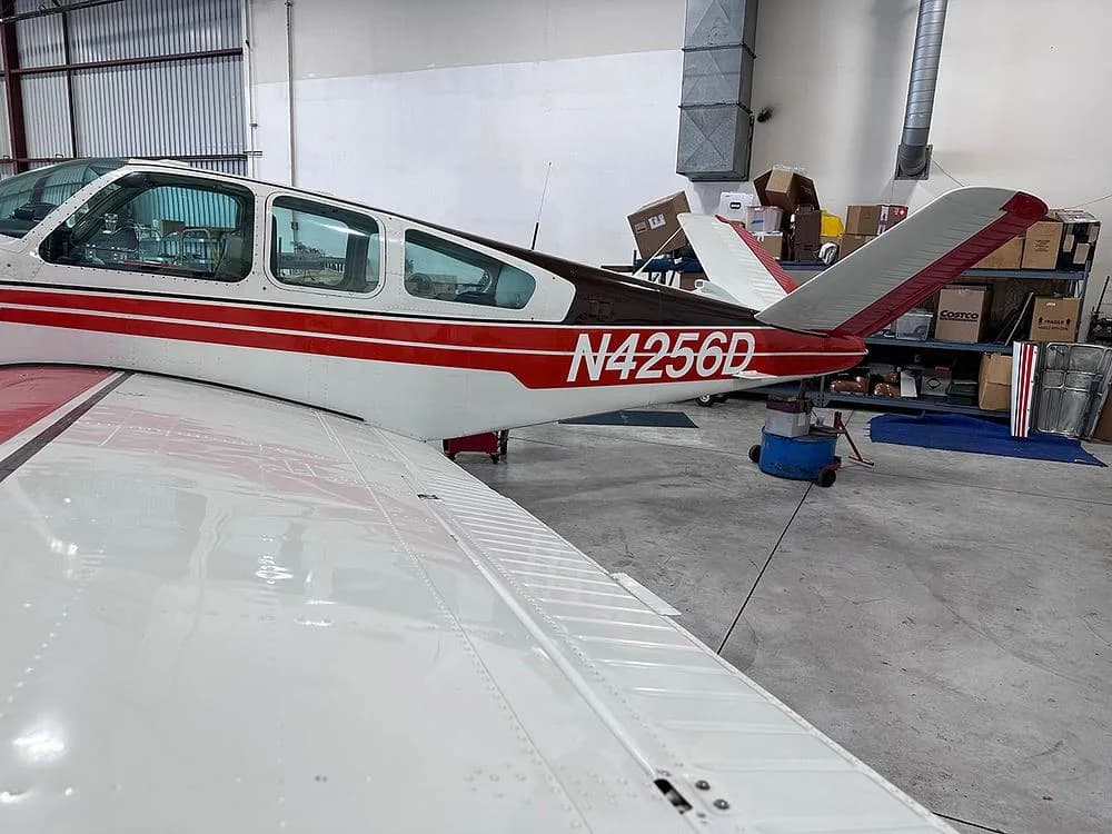 Rear view of a white and red aircraft with registration N4256D, parked in a hangar.