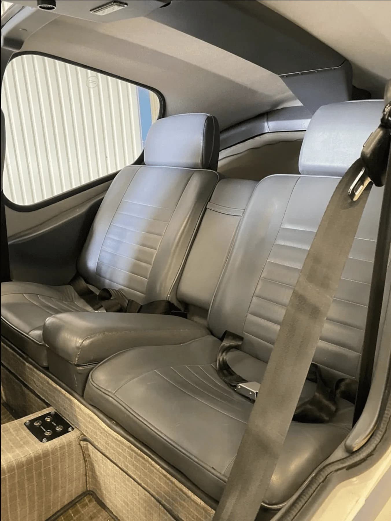 View of the gray leather rear passenger seats inside the aircraft cabin.
