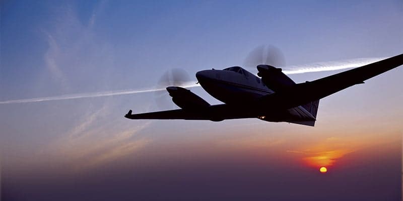 Silhouette of a King Air 260 flying at sunset.