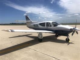 A white and blue aircraft with tail number N114K is parked on the tarmac.