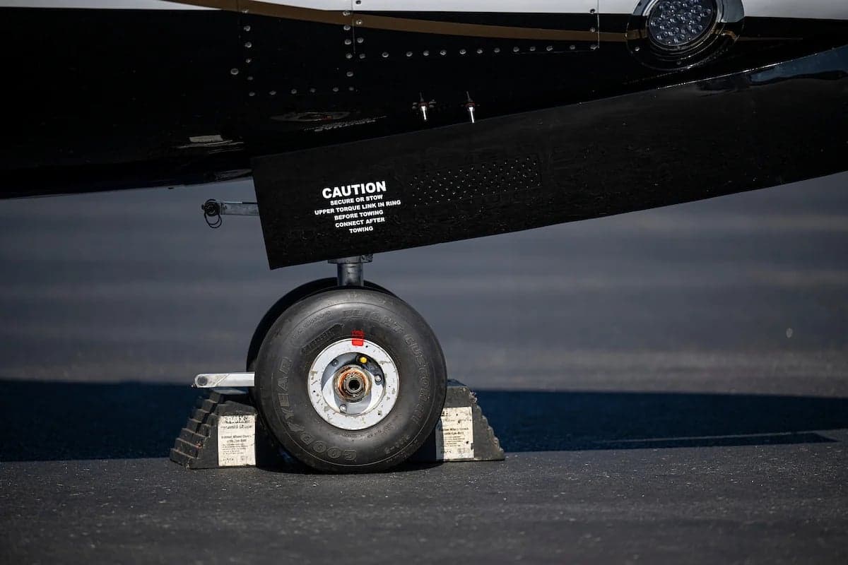 Close up of the landing gear and tire of the N33EW aircraft with chocks.