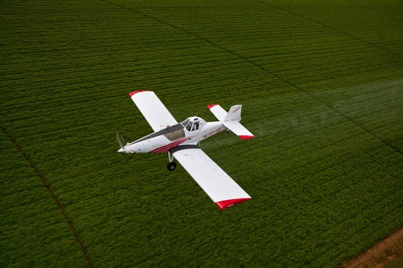 Aerial view of a Thrush 510G crop duster flying over a field.