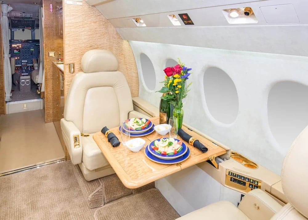 The interior of the Falcon aircraft features a table set for a meal.