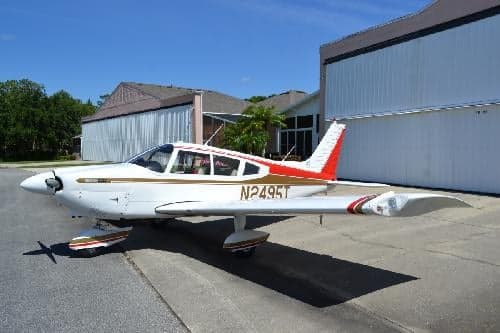 Piper PA-28-181 Archer II, registration N2495T, parked on the tarmac in front of a hangar.
