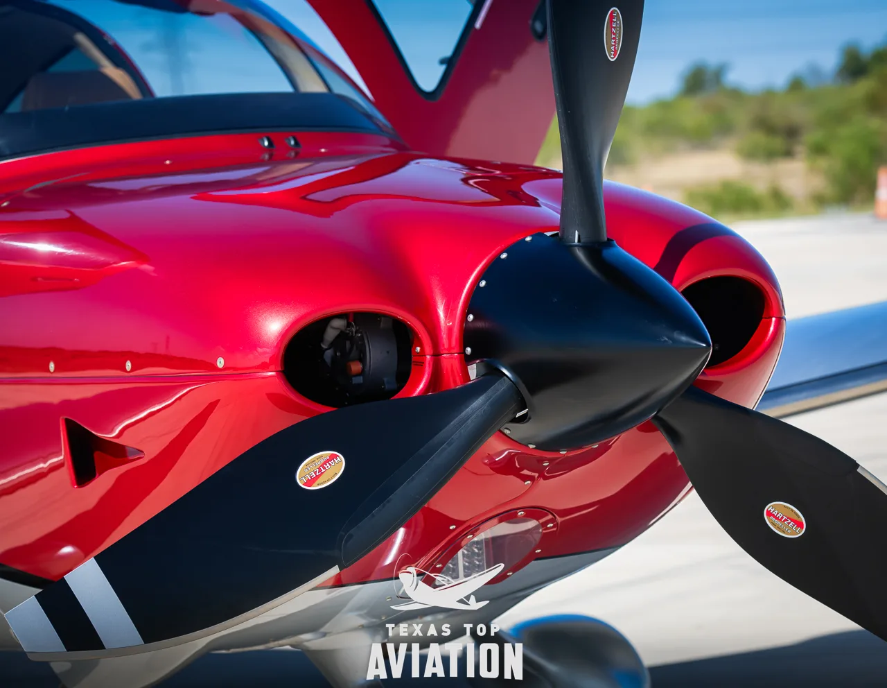 A close-up view of the red cowling and black propeller of a Cirrus SR22T GTS aircraft.