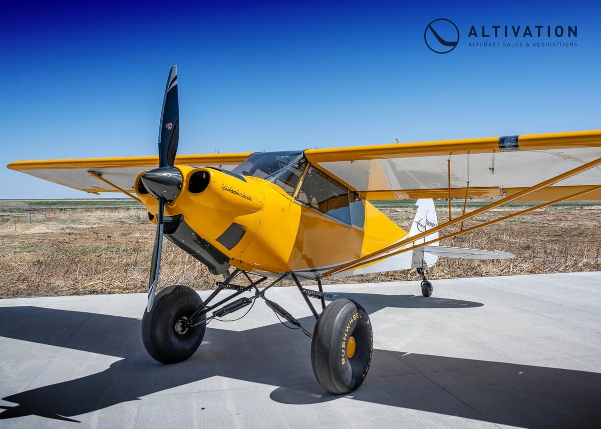 A yellow and white Carbon Cub aircraft with tundra tires.