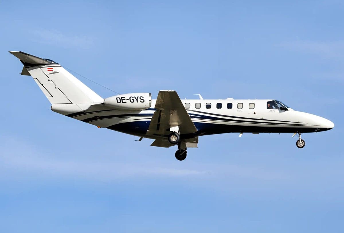The OE-GYS aircraft is shown in flight against a blue sky.