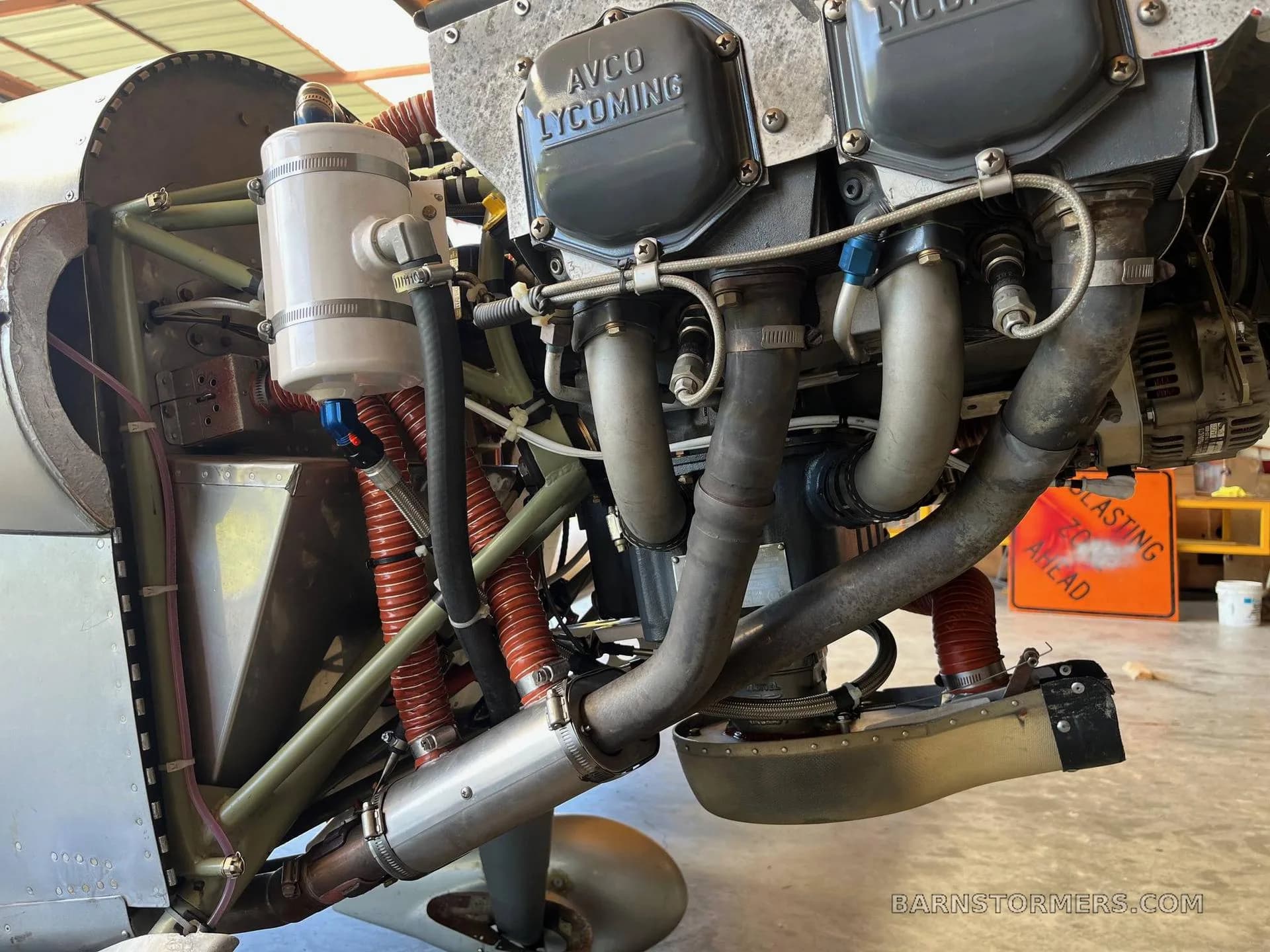 A detailed view of an AVCO Lycoming aircraft engine with exhaust pipes and various hoses.